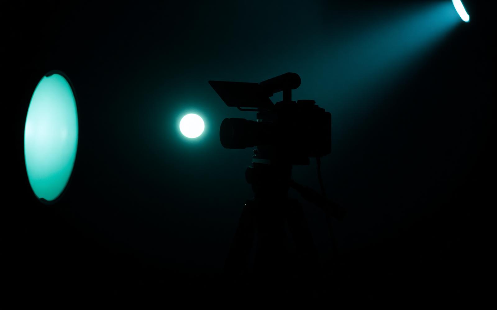 Cámara de cine en silueta dentro de una sala oscura